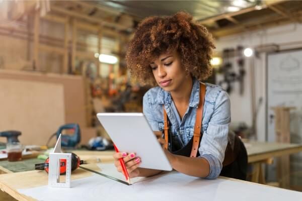 Mulher concentrada utilizando aplicativo de produtividade em seu tablet.