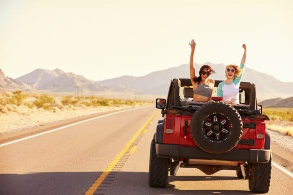Um carro na estrada com belas paisagens ao redor, representando a aventura de uma viagem de carro.